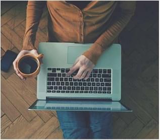 Person working on a laptop while sitting on floor