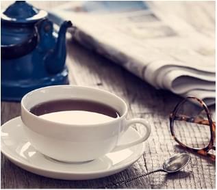 Cup of coffee next to newspaper